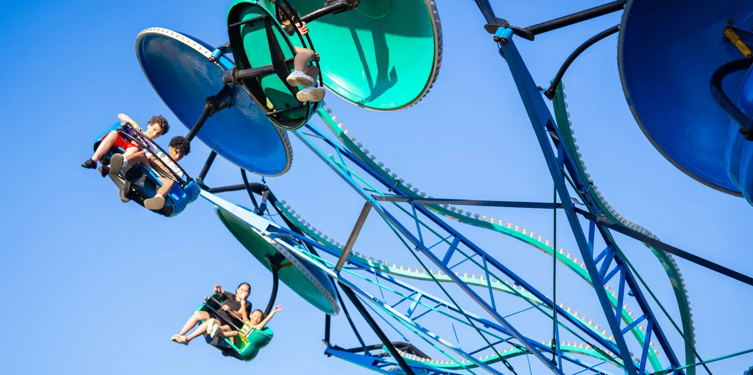 People on Paratrooper ride flying through air with blue sky in background