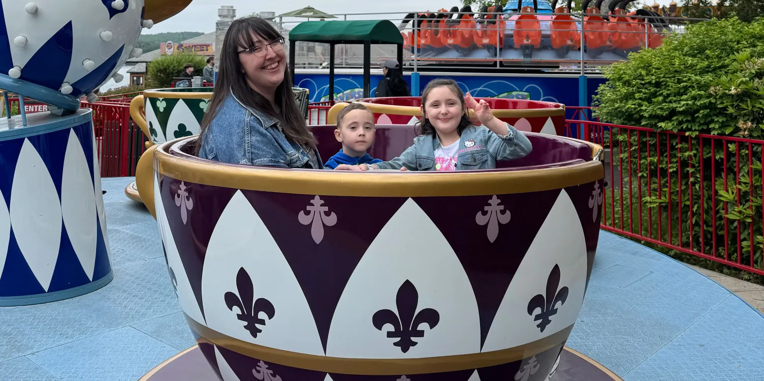 Adult and two children sitting in Crazy Cups ride