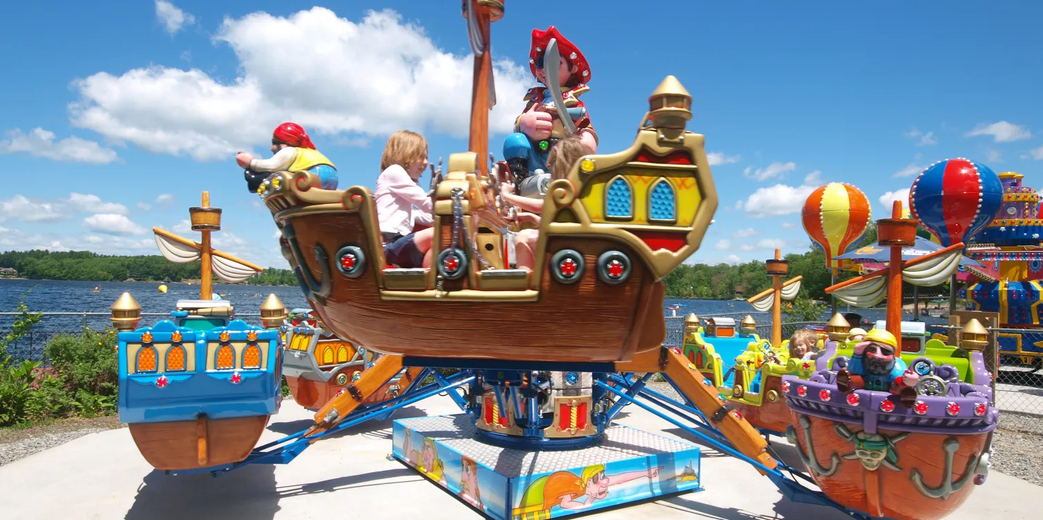 Children on Skippers Clippers ride, with blue sky and Lake Quassapaug in backgroudnd