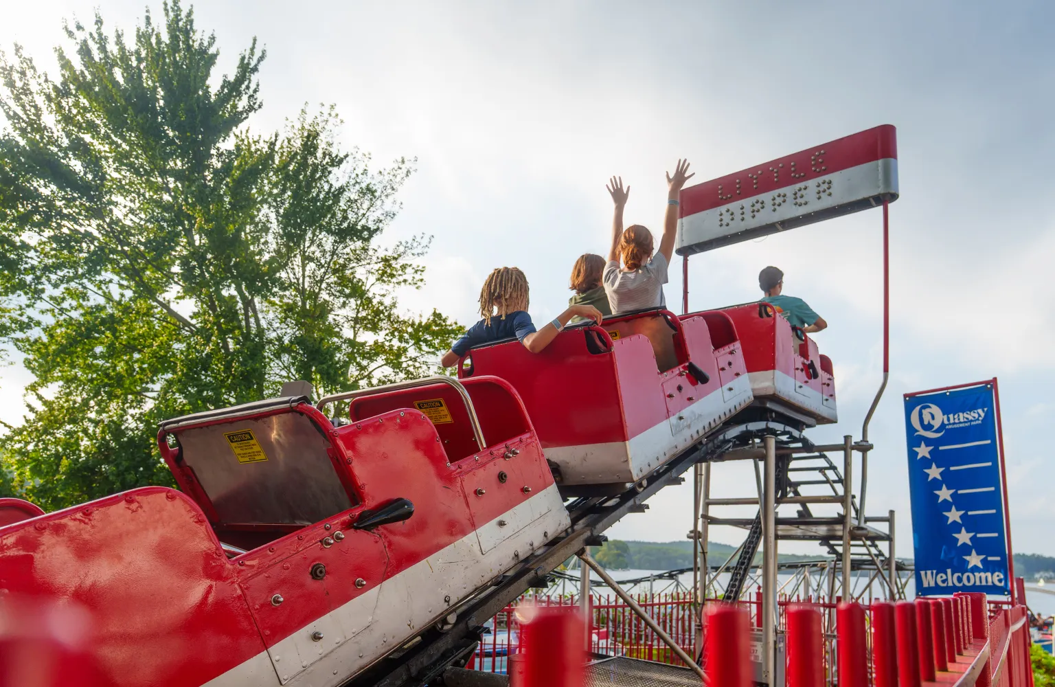 Image of children on Little Dipper ride, with arms up in air, about to go down the small drop