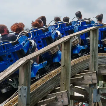 Showing the backs of people's heads on Wooden Warrior roller coaster, about to go over drop