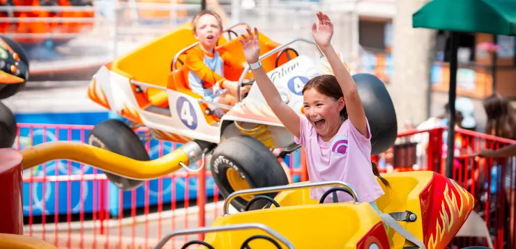 Children in cars on Bouncing Buggies ride, with arms up in air