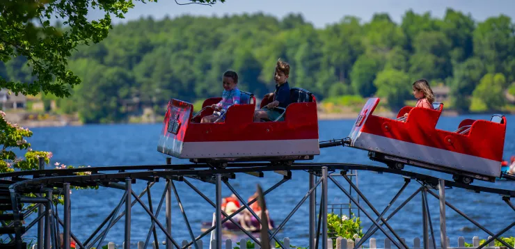 Two children on Little Dipper coaster, with Lake Quassapaug in the background