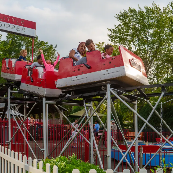 Adult and children on Little Dipper coaster, with arms up in air