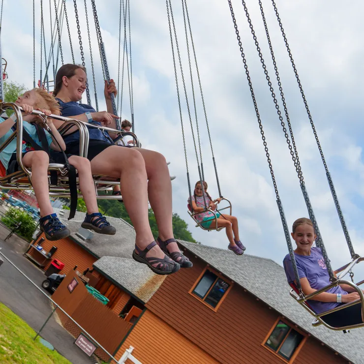 Adult and children sitting in swings on Aladdin Wave Swinger Ride