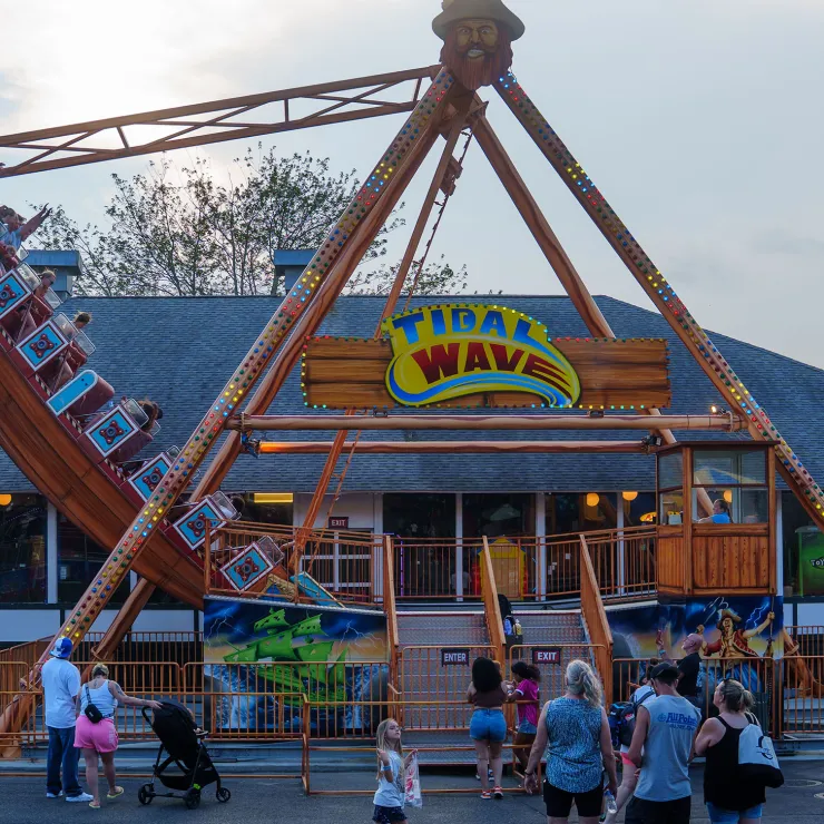 Tidal Wave swinging ship ride with people on ride and onlookers watching