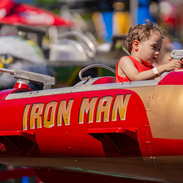 Child on Jet Fighters ride, sitting in jet labeled Iron Man