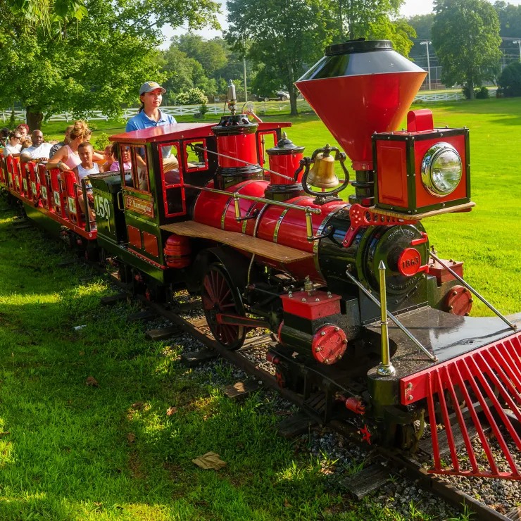 Quassy employee operating Quassy Train in theme park, with people on ride
