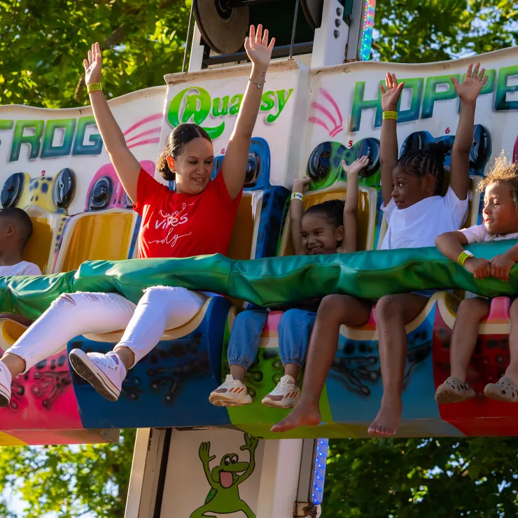 Adult and children on Frog Hopper ride with arms in air