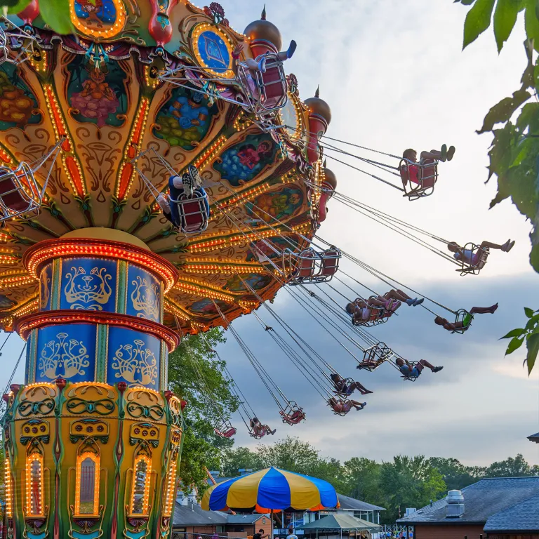 People in swings on Aladdin Swings ride with skyline in background